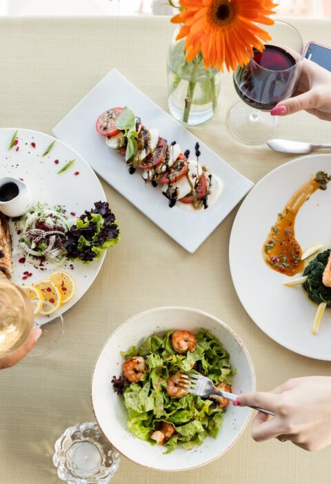 person holding fork and knife slicing vegetable on white ceramic plate